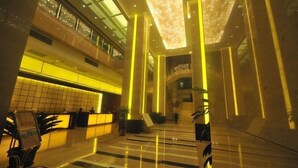 Eine moderne Hotelhalle mit einer zentralen Treppe, spiegelnden Böden und einer Rezeption.