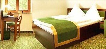 A hotel room with a bed, a desk, a chair, and a window.