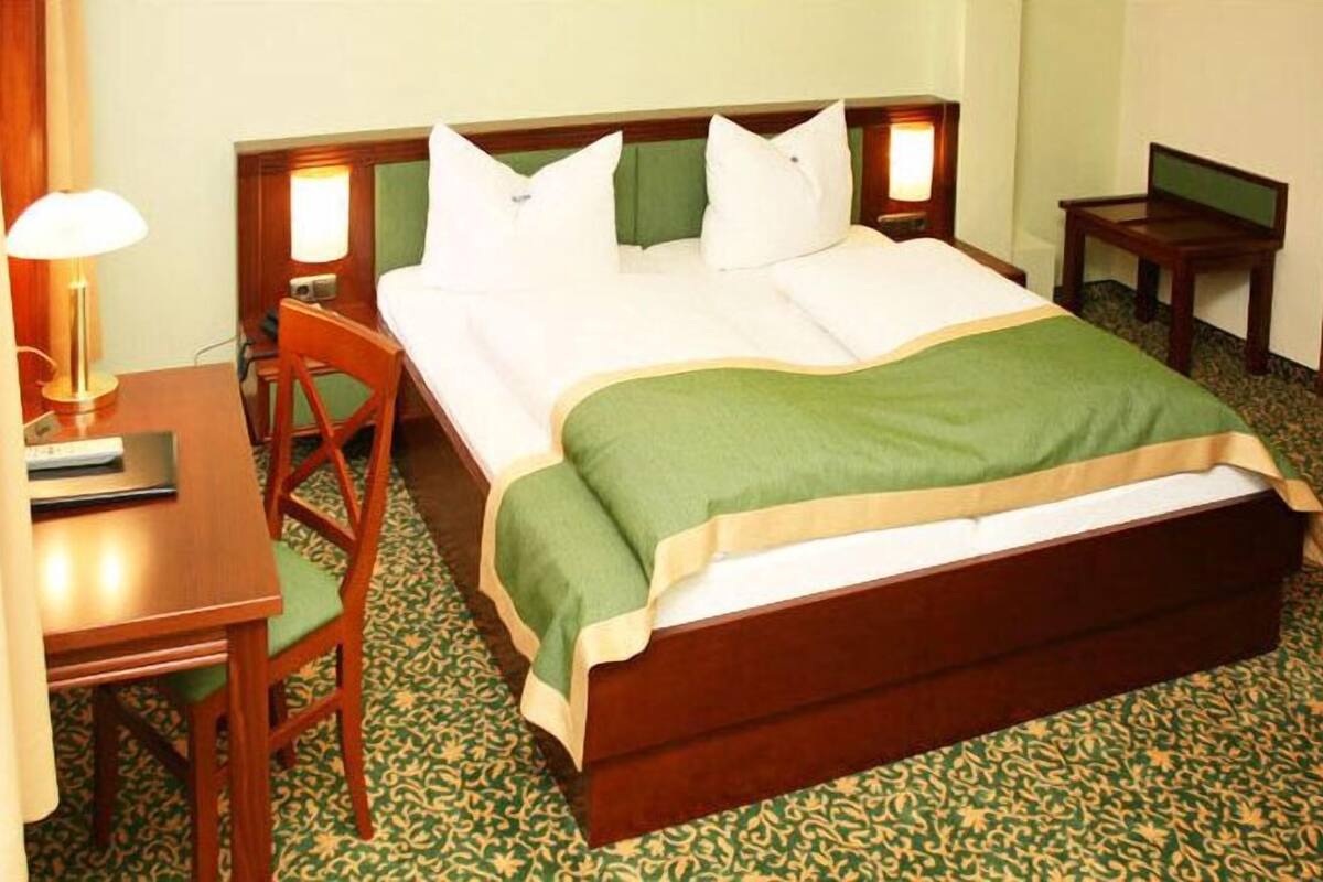 Ein Hotelzimmer mit Bett, Schreibtisch, Stuhl und Nachttisch.