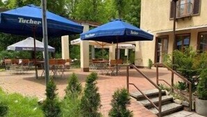 Un espace extérieur aménagé en terrasse, avec des parasols bleus portant l’inscription « Tucher », des marches en pierre et des plantes en pot.