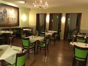 A restaurant with round tables, green chairs, and a chandelier. - Park-hotel Zirndorf (ZIRNDORF)