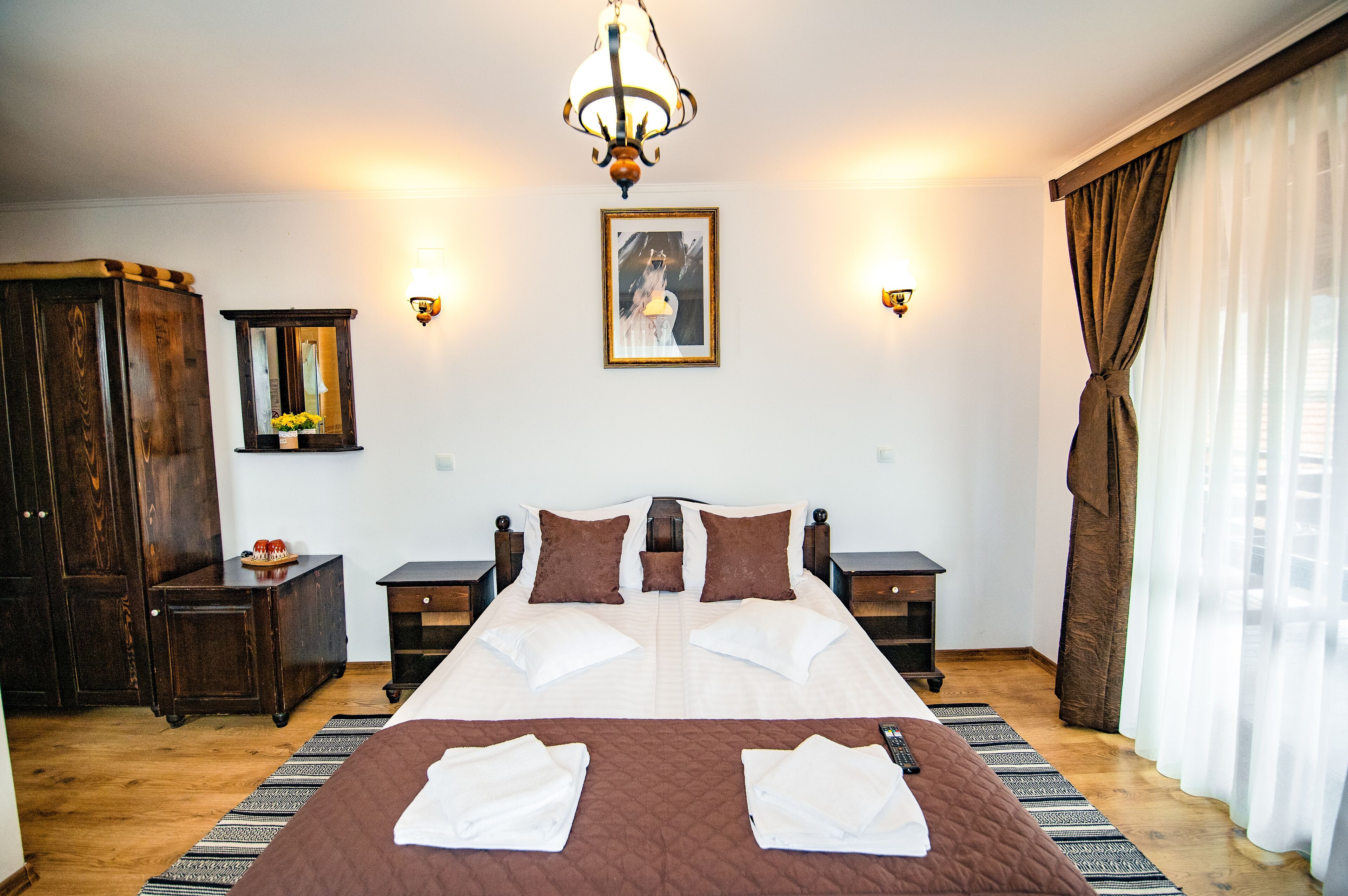 Ein Hotelzimmer mit einem großen Bett, Holzmöbeln, einem Chandelier und einem Gemälde an der Wand.
