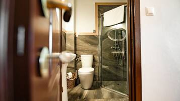A bathroom with a toilet, a shower, and a glass-enclosed shower area.