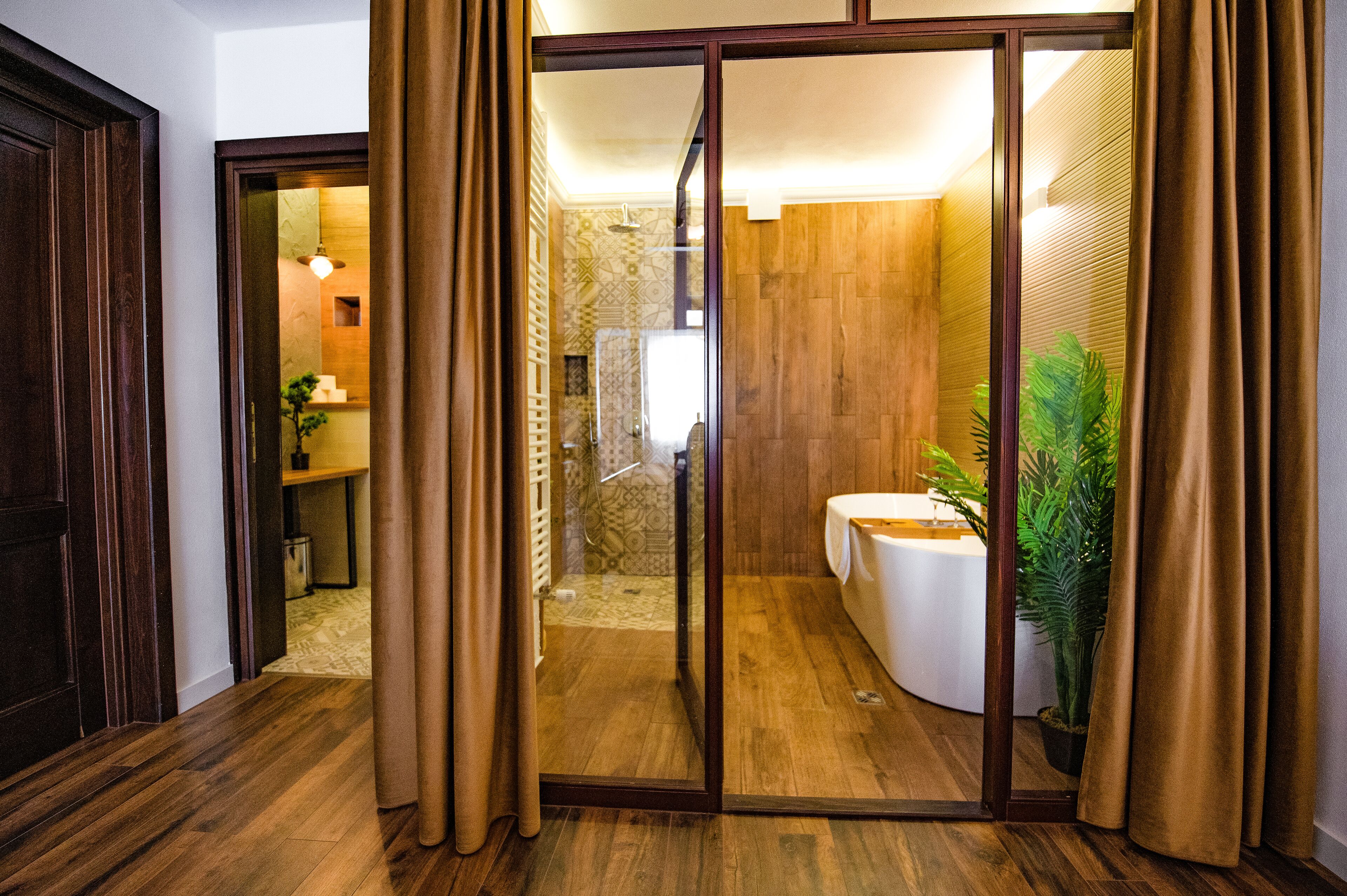 Un baño moderno con cabina de ducha de vidrio, una bañera blanca y una planta en maceta.