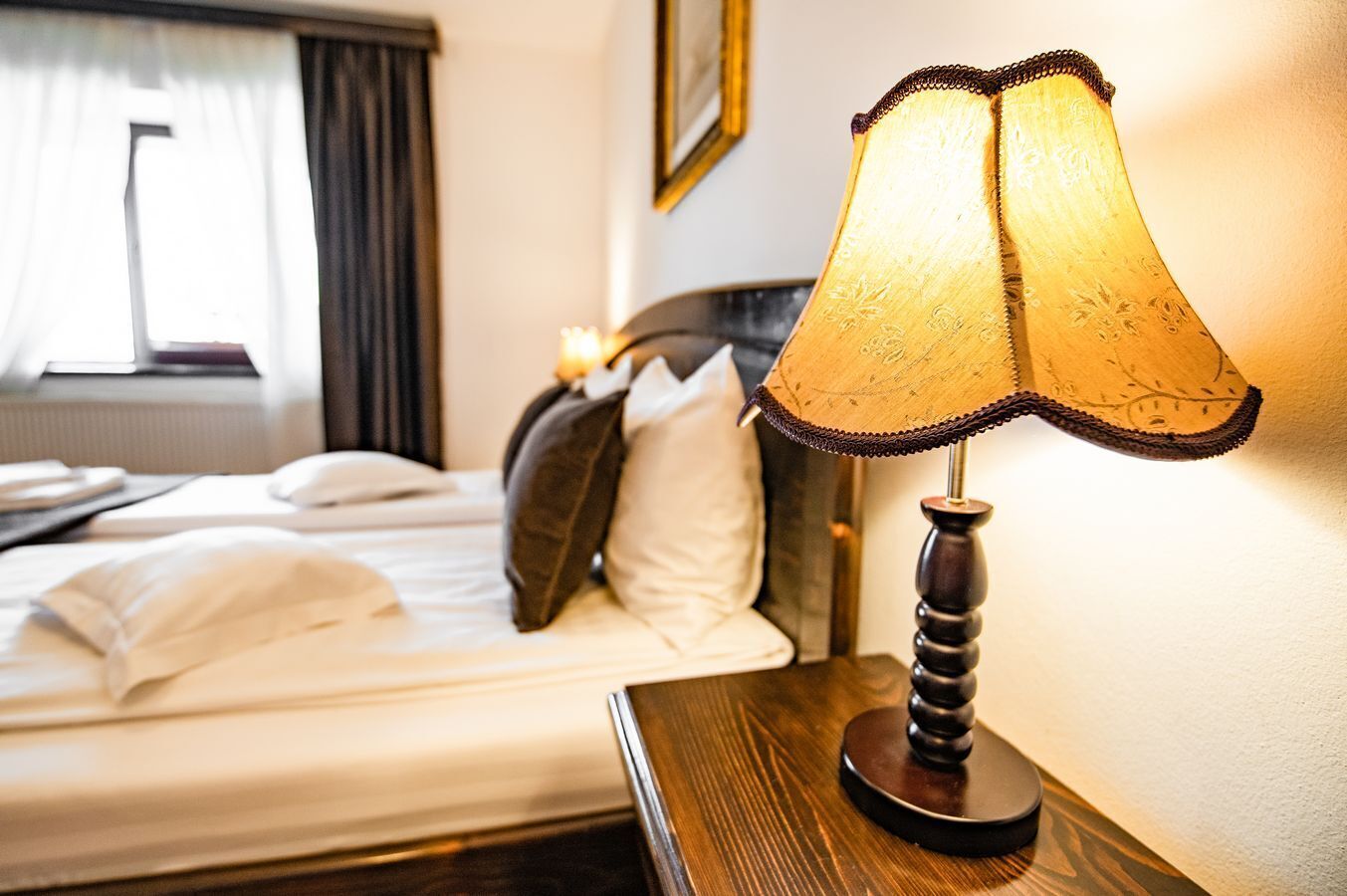 A neatly made bed with pillows and a bedside table with a lamp.