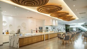 Een modern restaurant met een marmeren toonbank, decoratieve rieten plafond en een ruime eetruimte met houten stoelen.