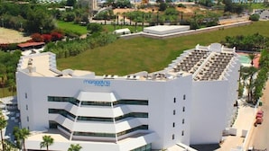 Een modern hotel met een witte gevel, meerdere verdiepingen en een terras op het dak.