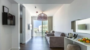 Een moderne woonkamer met een bank, een salontafel en een televisie. Op de achtergrond is een eethoek met een tafel en stoelen.