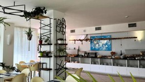 Een moderne eetruimte met een bar, witte muren en een wereldkaart muurschildering.