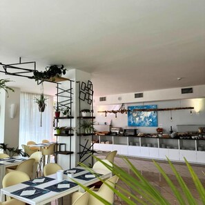 A modern dining area with a bar, white walls, and a world map mural.