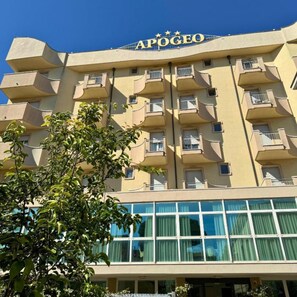 Un hôtel à plusieurs étages, doté de balcons et d’une enseigne indiquant « APOGEO ».