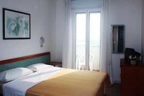 Une chambre d’hôtel comprenant un lit, une table de chevet, une commode, une fenêtre avec des rideaux et une vue sur l’extérieur.