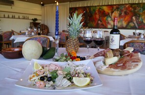 A dining table set with various dishes, a bottle of wine, and a pineapple centerpiece.
