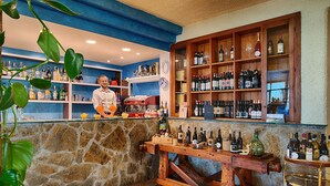 Un espace bar avec des étagères remplies de bouteilles de toutes sortes, un comptoir en bois et un mur en pierre.