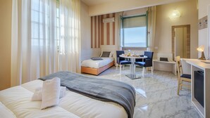 Une chambre d’hôtel avec un lit, un petit bureau, une chaise, une table et une fenêtre avec des rideaux.