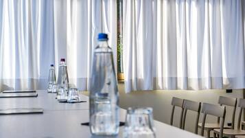 Un salón de conferencias con una mesa larga, sillas y botellas de agua.