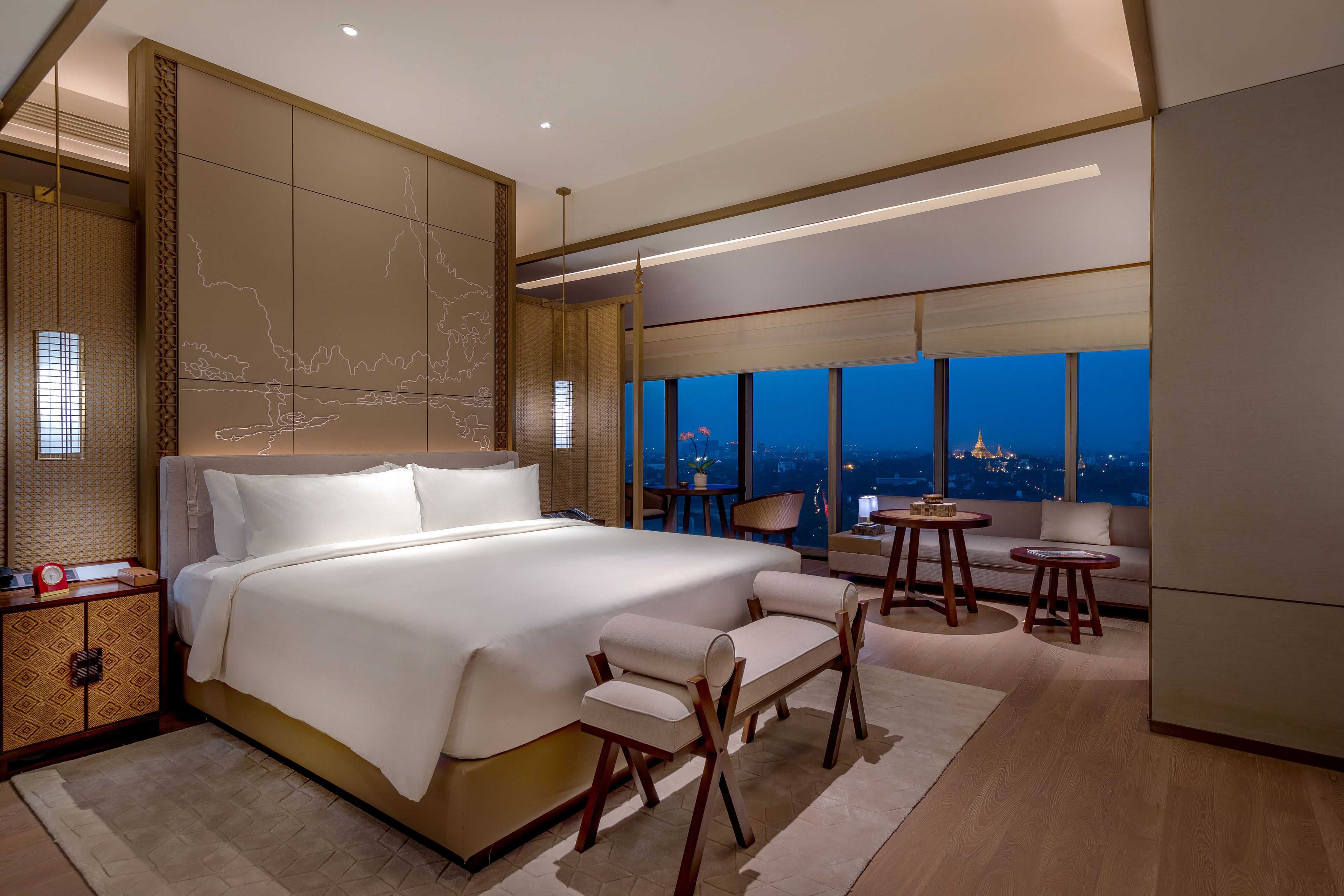 Una habitación de hotel moderna con una cama grande, zona de estar y vistas a la ciudad.