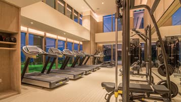 Ein Fitnessstudio mit Laufbändern, Kraftgeräten und einer Spiegelwand.