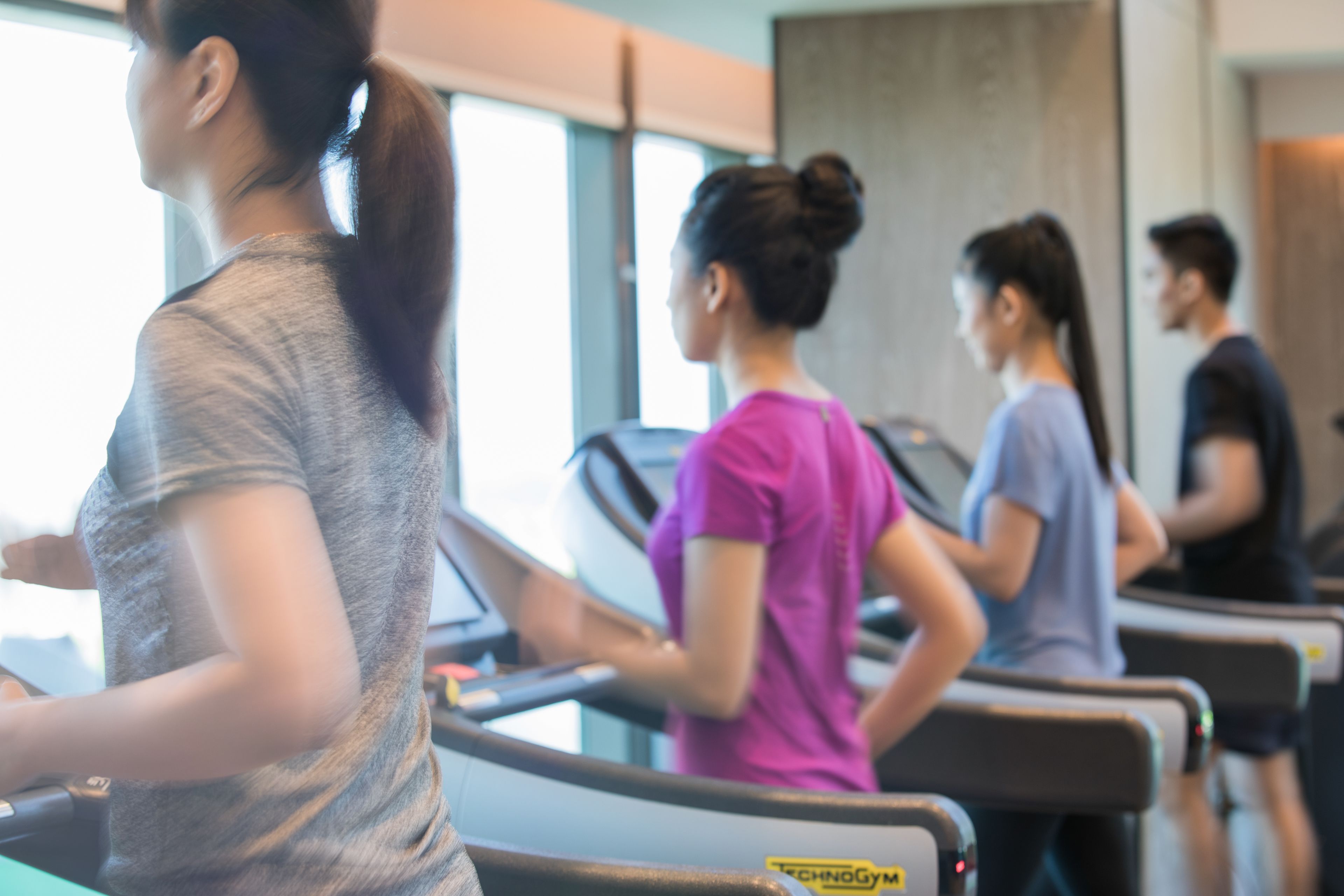 Un gimnasio con cintas de correr y un amplio ventanal.