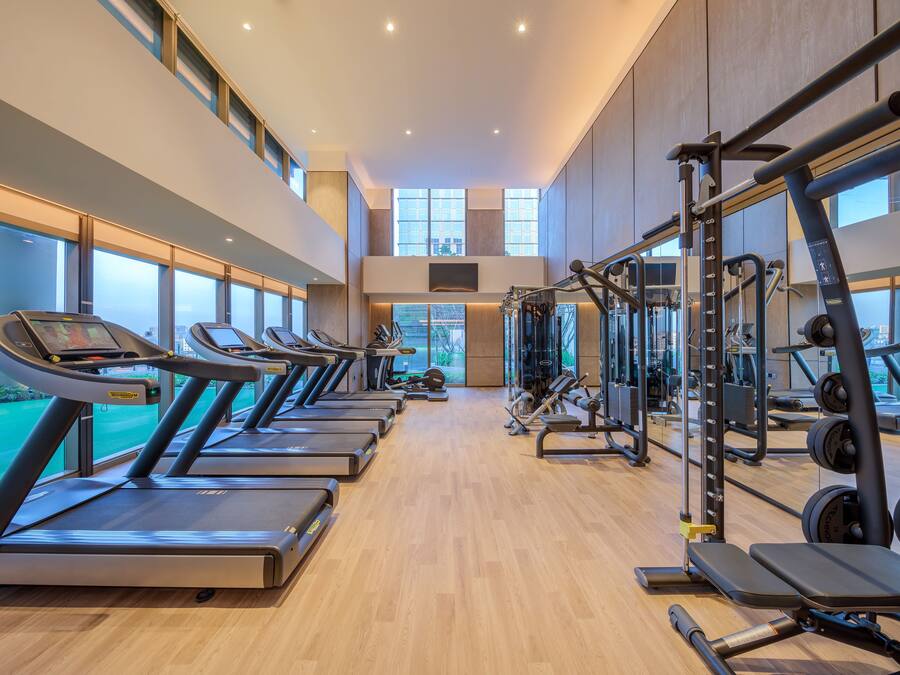 A gym with treadmills, weight machines, and a large window offering a view of the city.