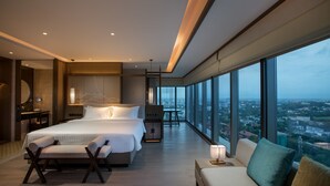 Een moderne hotelkamer met een groot bed, een zithoek en uitzicht over de stad.