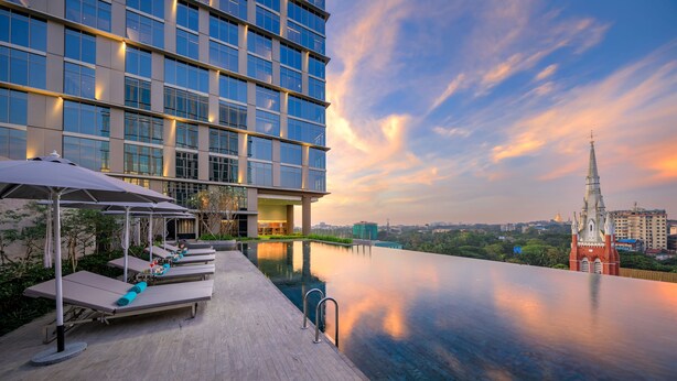 Een modern hotel met een dakterraszwembad, ligbedden en parasols.