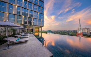 A modern hotel with a rooftop infinity pool, lounge chairs, and umbrellas. - Pan Pacific Yangon (Yangon)