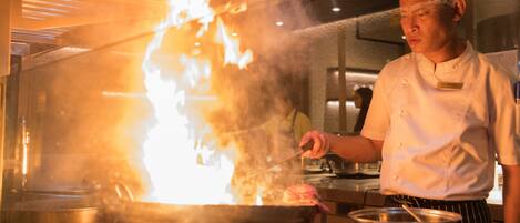 A chef cooking with a large flame in a professional kitchen.