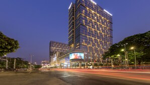 Een hoog hotel met een opvallend “Pan Pacific” bord, meerdere verdiepingen en een groot digitaal reclamebord.