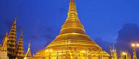 A large, golden pagoda with multiple tiers and intricate details, surrounded by smaller structures and a crowd of people.