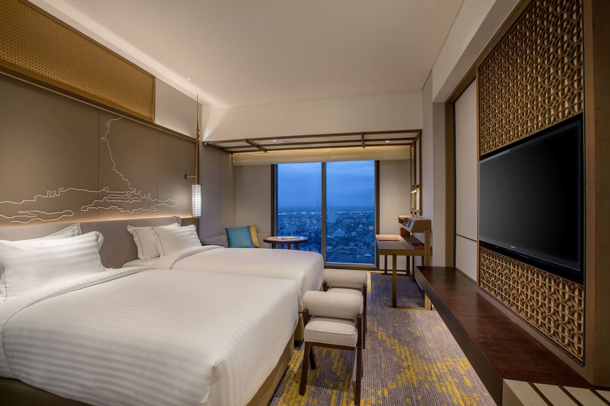 A hotel room with a large bed, a desk, a chair, and a TV.