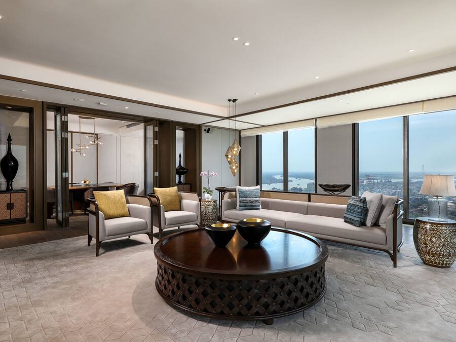 A modern living room with a round coffee table, a sofa, and a view of the city through large windows.