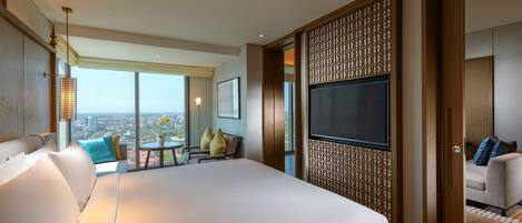 Una habitación de hotel moderna con una cama grande, un televisor, un balcón con vistas a la ciudad y un panel decorativo en la pared.