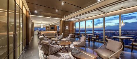 A modern lounge with high ceilings, large windows, and comfortable seating areas.
