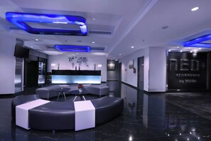 Eine moderne Lobby mit Sitzgelegenheit, einer Rezeption und einer Wand mit einer Weltkarte und Kunstwerken.