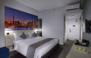 A hotel room with a bed, a cityscape mural, a desk with a computer, and a small kitchenette. - Starray Hotel Kebayoran (Jakarta)