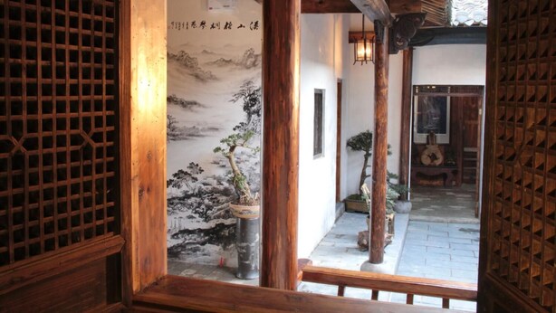 A traditional wooden corridor with a shoji screen, a bonsai tree, and a calligraphy scroll. - Huangshan Xishan Wutongqinyuan (Huangshan)