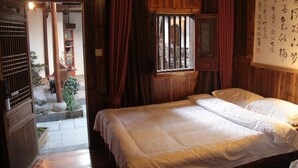 A traditional wooden room with a bed, a window with bars, and a wooden door. - Huangshan Xishan Wutongqinyuan (Huangshan)