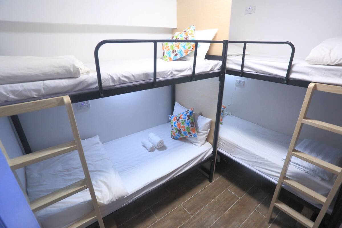 A bunk bed room with two beds, each with white bedding and pillows. There are wooden ladders for access to the beds.