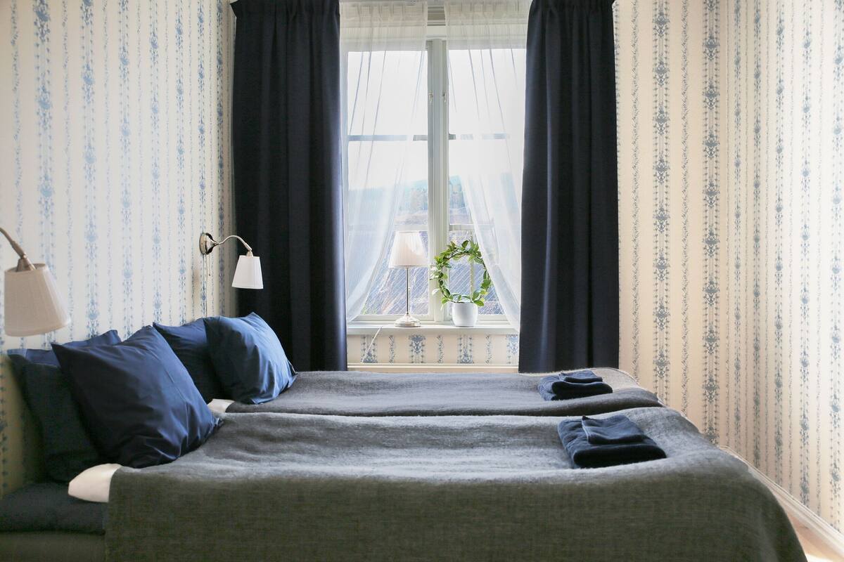 Une chambre d’hôtel avec un lit, une lampe et une vue sur un immeuble par la fenêtre.