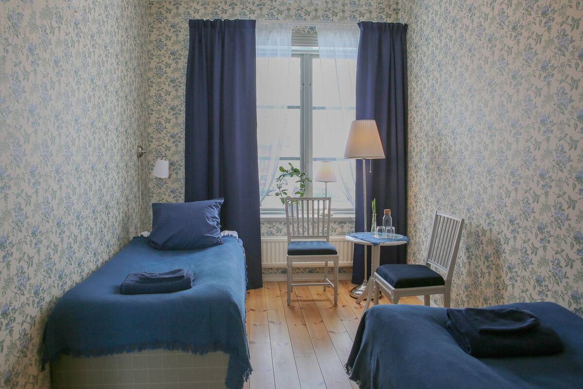 Une chambre avec deux lits, une petite table avec une lampe et une chaise.