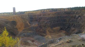 A large open pit mine with steep, terraced walls and a winding road.