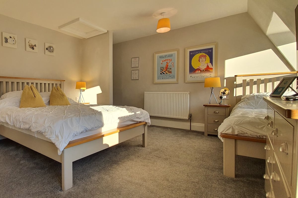 Une chambre à coucher comprenant un lit, des tables de chevet, une armoire et un bureau.