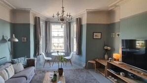 Ein Wohnzimmer mit Sofa, Couchtisch, Fernseher und einem Essbereich mit Stühlen und Tisch.