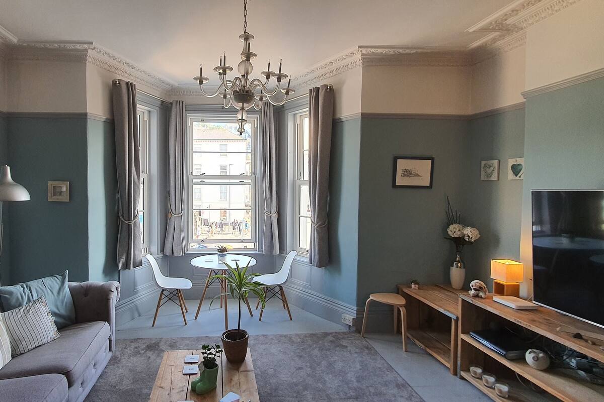 Un salon comprenant un canapé, une table basse, un téléviseur et un coin repas avec des chaises et une table.