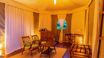 A cozy room with a wooden table, two chairs, a cabinet, and a window with curtains.