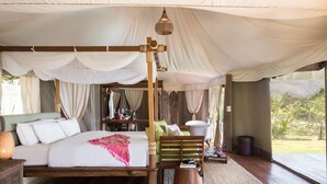Un dormitorio amplio con una cama grande, cabecera de madera y vistas al exterior.
