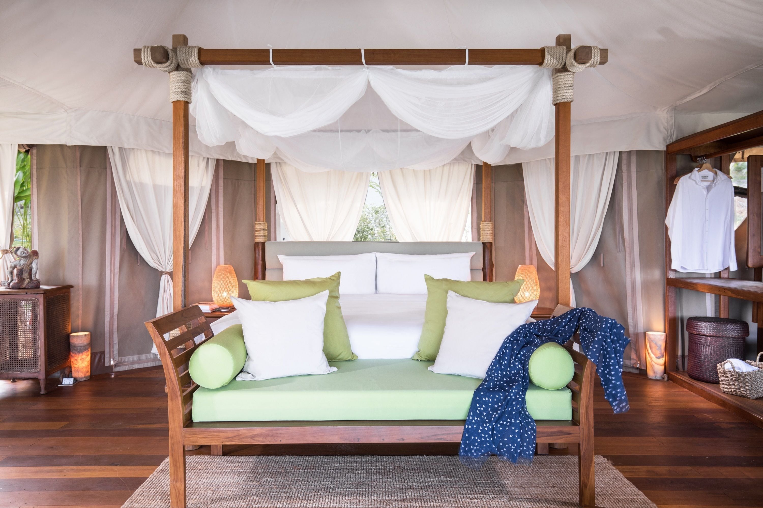Un lit à baldaquin à quatre poteaux, avec un matelas vert, des oreillers blancs et une couverture bleue.