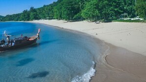Un bote en una playa con agua azul cristalina y orilla arenosa.