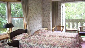 A bedroom with two beds, a nightstand, a lamp, and a chair. - Naeba Springs Hotel (Yuzawa)
